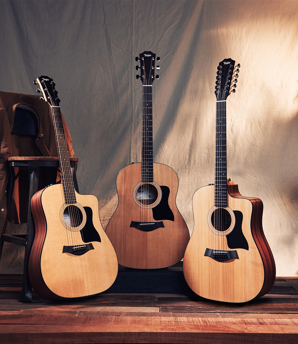 Three guitars on stands in front of a stool and backdrop