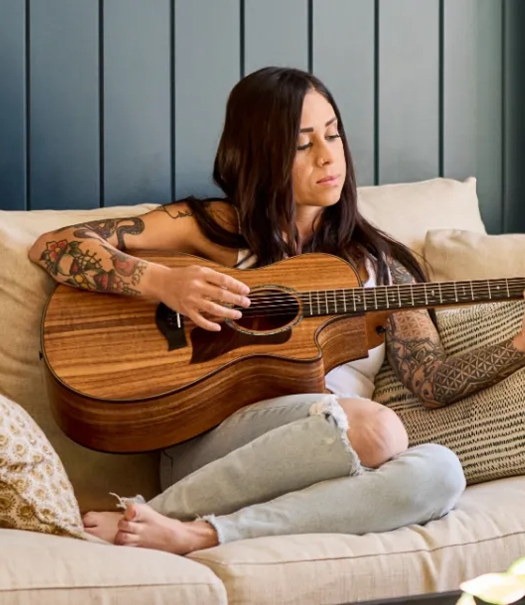 Girl sitting relaxed on couch playing guitar