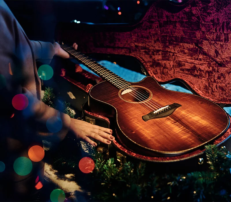 Picture of female opening a guitar case with christmas decorations around