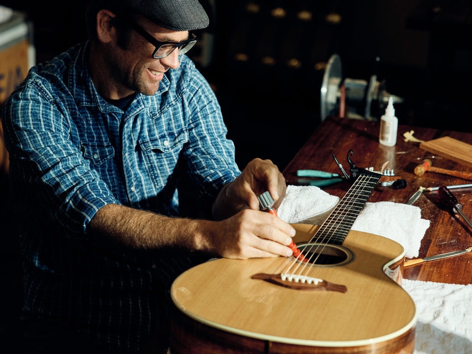 Image of Andy Powers adjusting a Taylor acoustic guitar with an Action Control Neck
