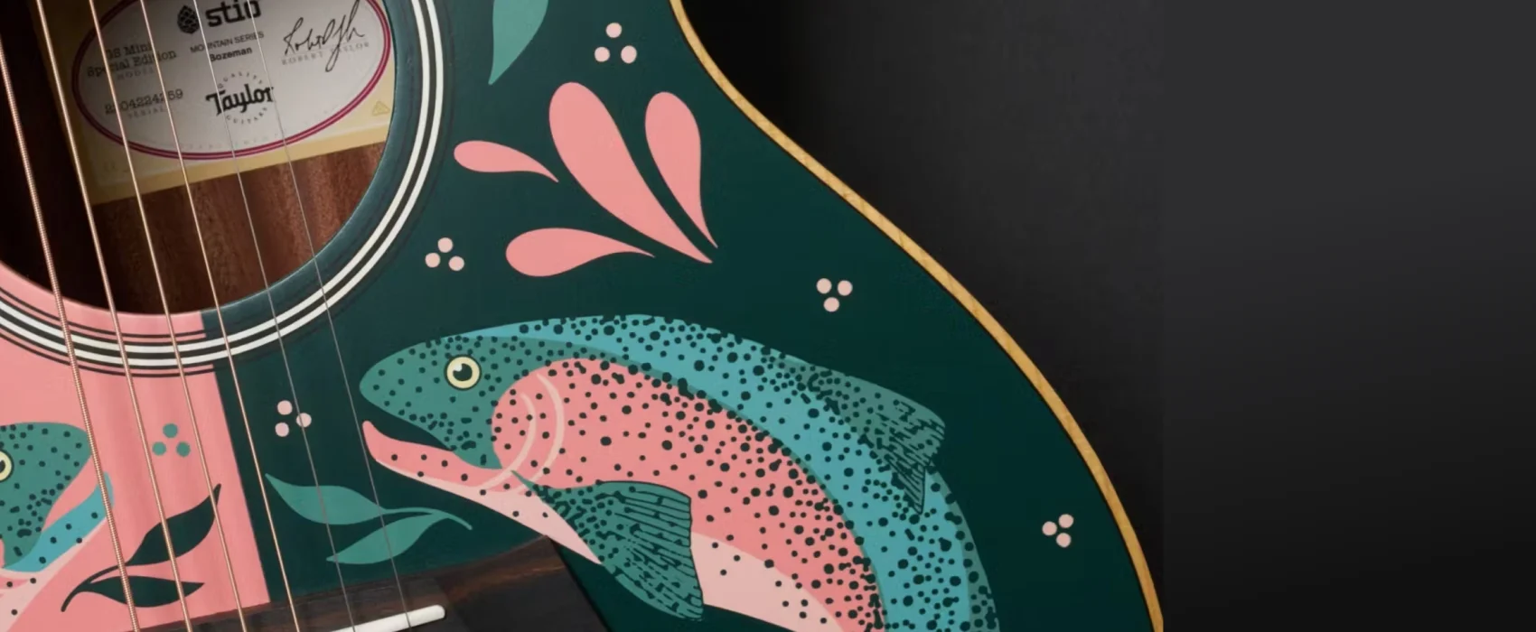 Hero closeup of a stio x taylor guitars guitar featuring a pink and green fish