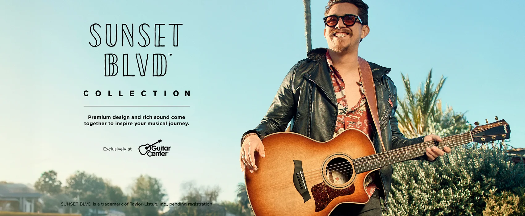 Man holding a Sunset Blvd guitar with a blue sky in the background