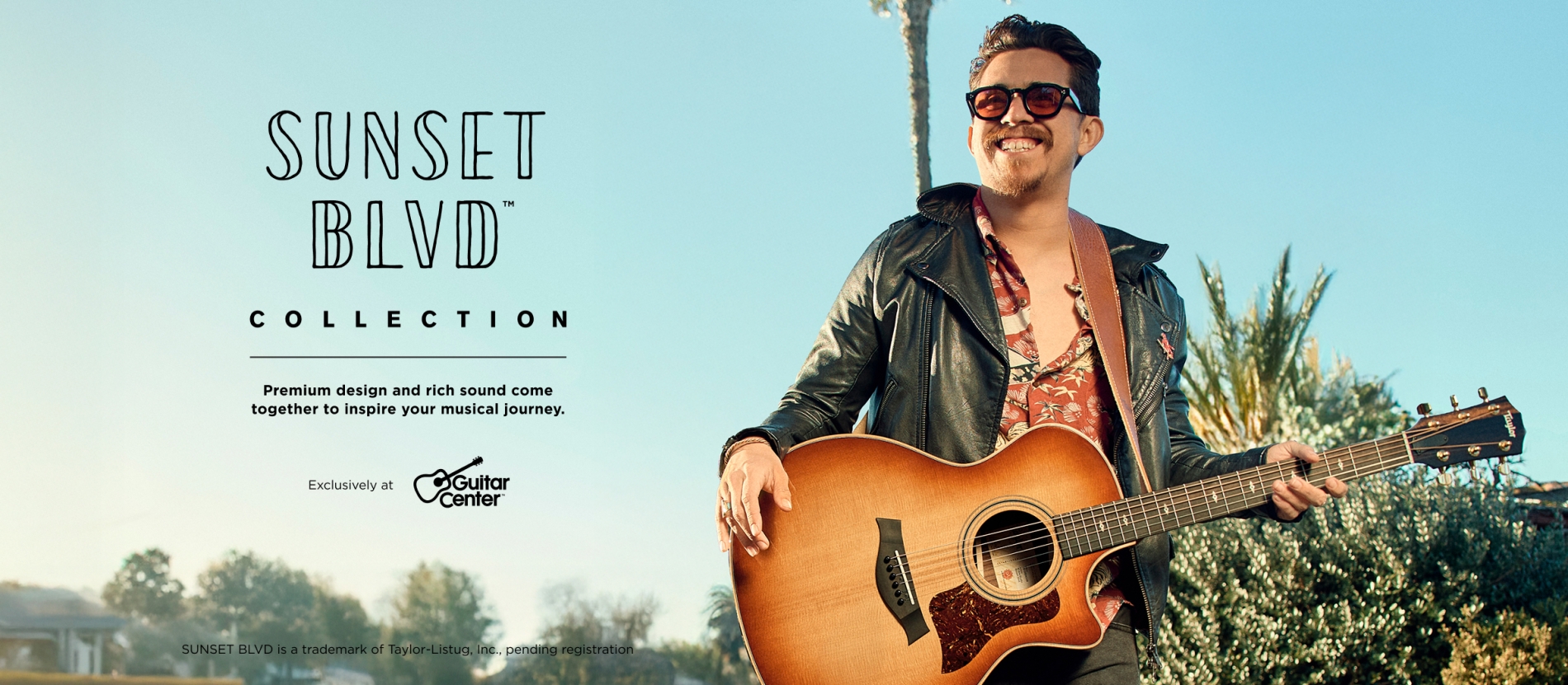 Man holding a Sunset Blvd guitar with a blue sky in the background