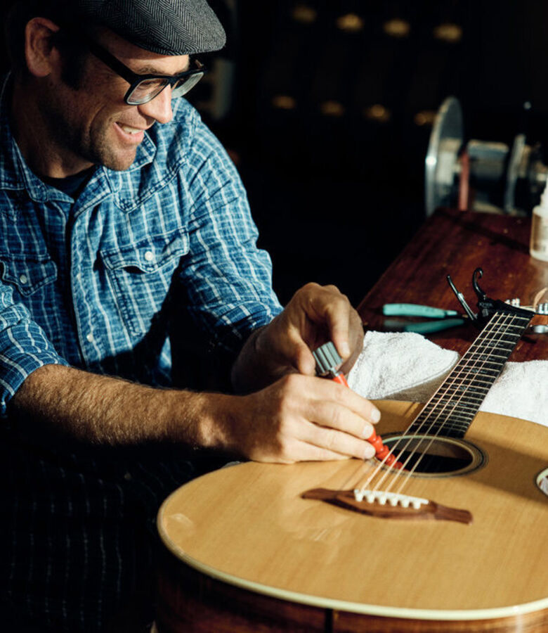 Image of Andy Powers adjusting a Taylor acoustic guitar with an Action Control Neck